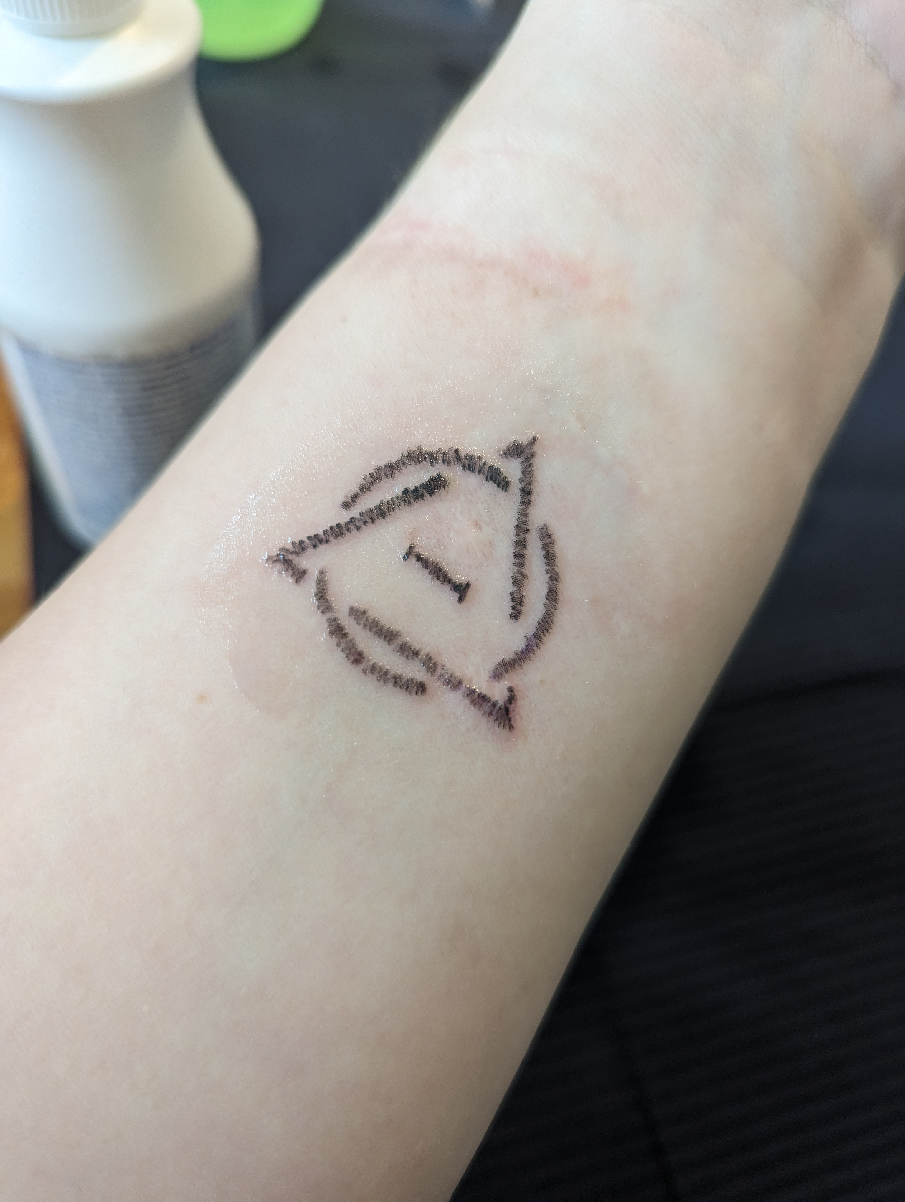 a tattoo of the therian symbol on one wrist