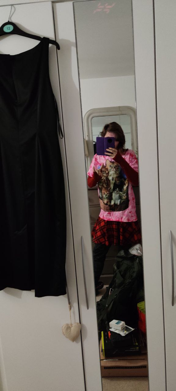 Me doing a \m/ in red knitted arm warmers, a pink shirt with cats on it, and a tartan red skirt