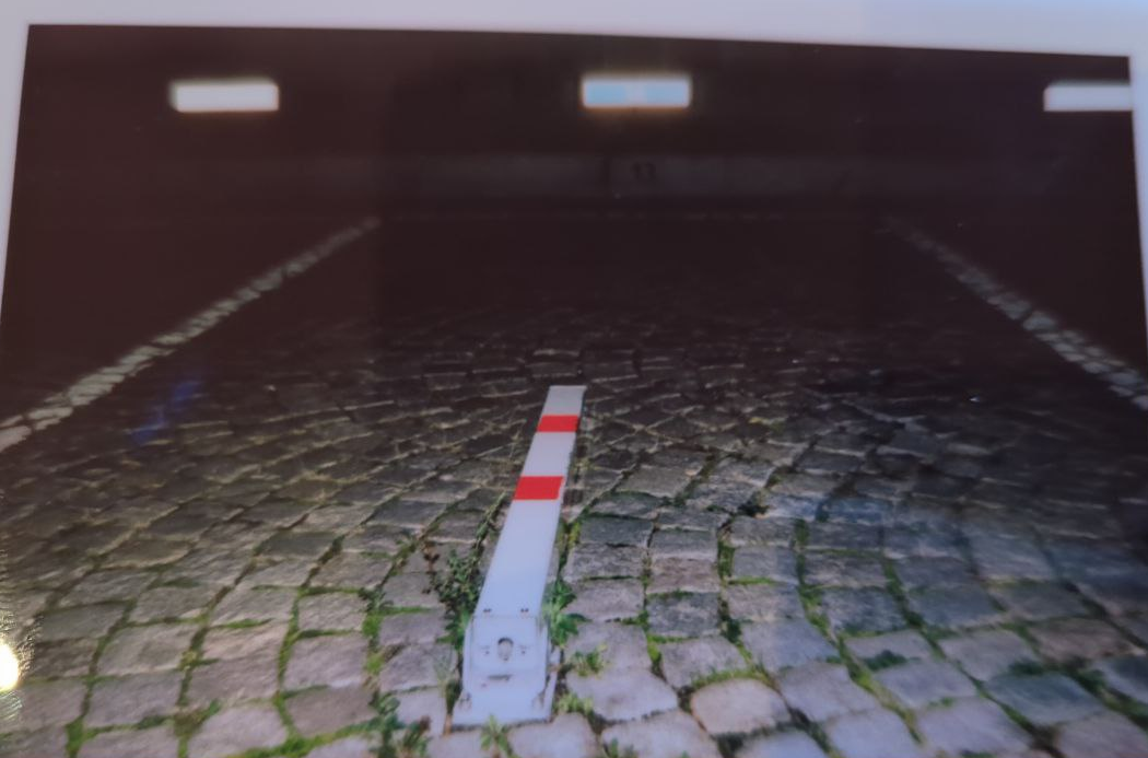 a red-striped white pole lying flat on circular stone tiles with some grass between them