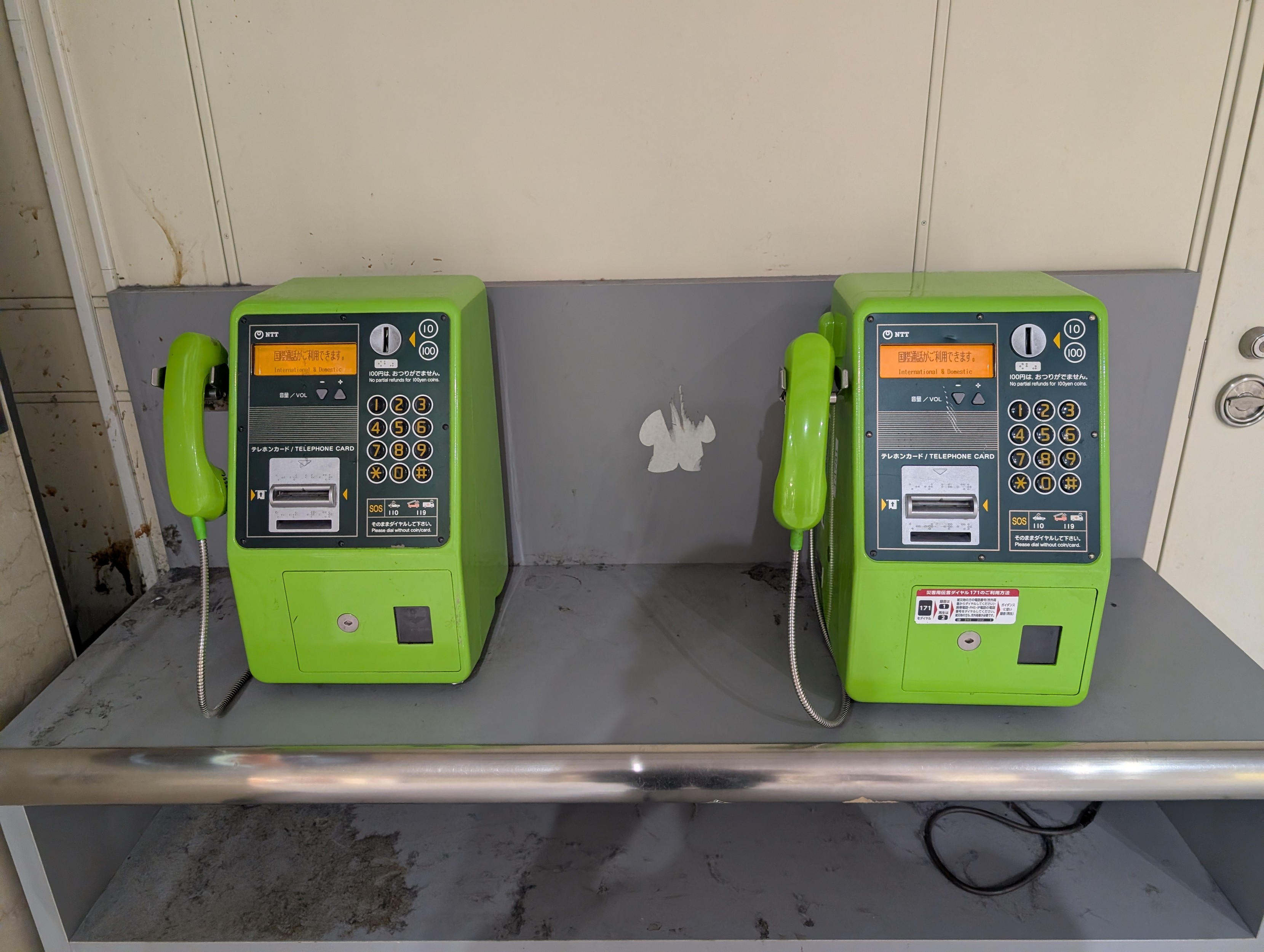 Two more green NTT phones sitting on a ledge. 