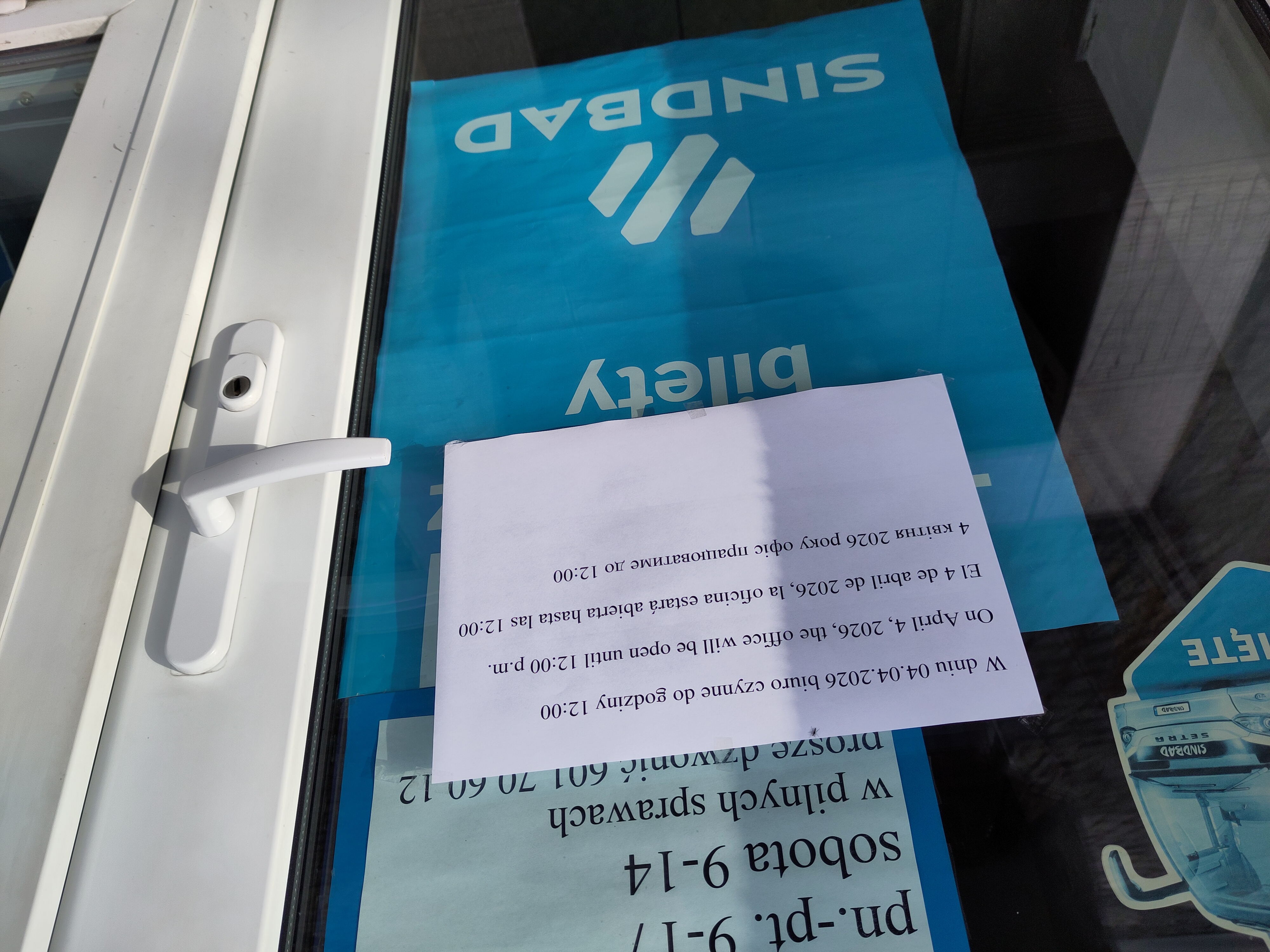 A sign in four languages informing that the office will only be open until 12pm