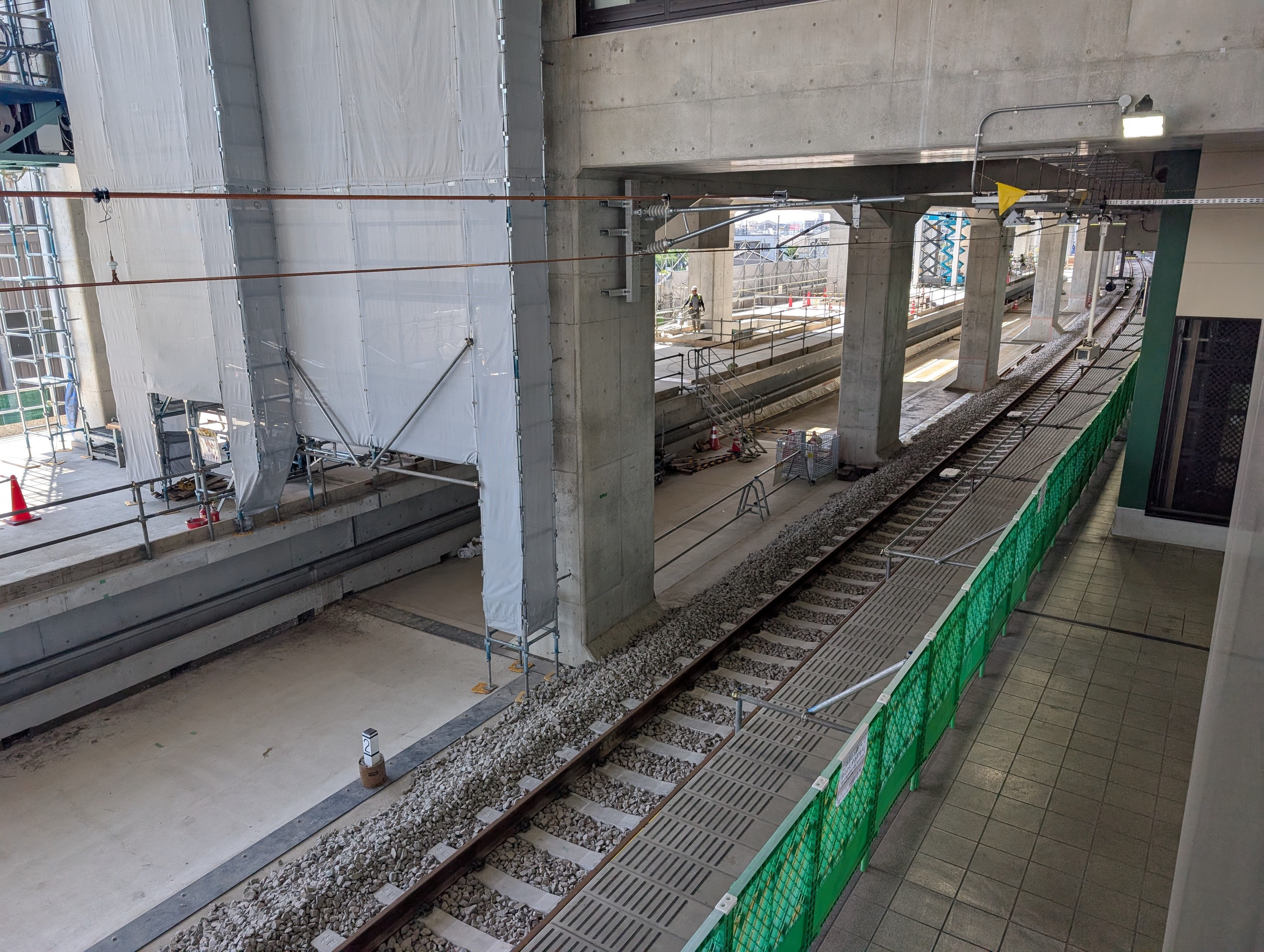Looking down on a worksite in a concrete building. There's a railway track running through it 