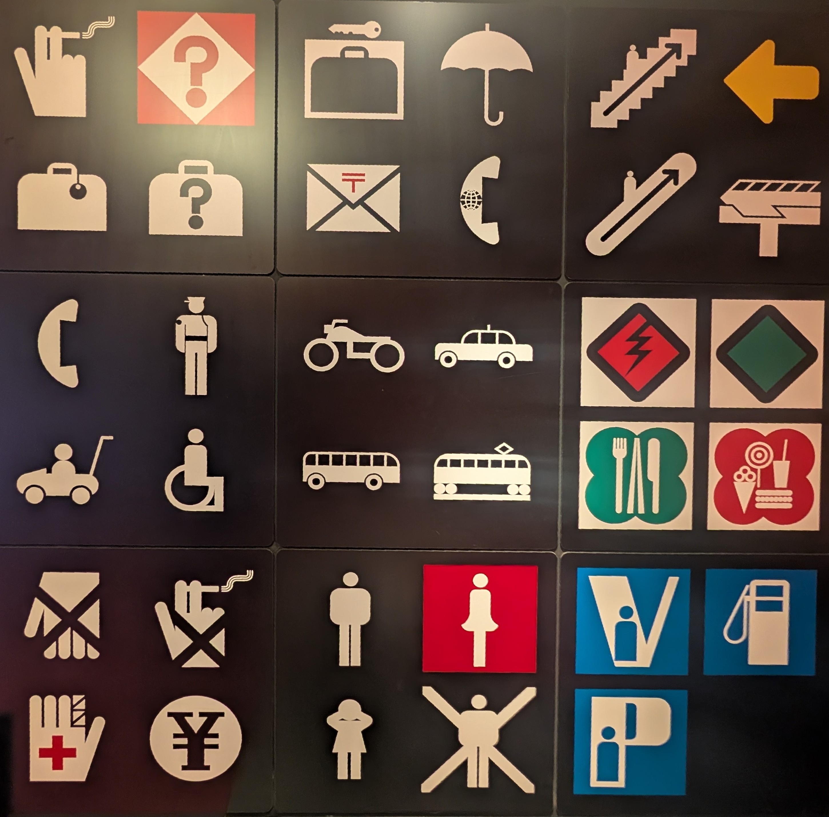 More icons. Top right to bottom left: 
- smoking
- question mark? Info? 
- luggage lockers
- umbrella 
- stairs up 
- luggage with tag 
- lost luggage 
- envelope? Post? 
- phone 
- escalator up 
- monorail 
- phone 
- officer? 
- stylised car/buggy thing?
- taxi 
- warning power 
- green diamond 
- pram 
- disabled 
- bus 
- metro 
- food 
- dessert 
- do not touch 
- no smoking 
- men 
- women 
- V with person 
- fuel 
- first aid 
- cash dispenser (Yen) 
- child(ren) 
- people not allowed 
- P with person 