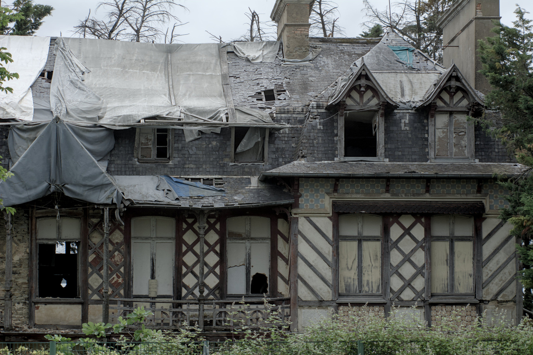 A decrepit manor in the style of old breton houses: the windows are busted, the roof is half gone and replaced with plastic tarps, but even those look faded. Everything looks faded. A decrepit manor in the style of old breton houses: the windows are busted, the roof is half gone and replaced with plastic tarps, but even those look faded. Everything looks faded.