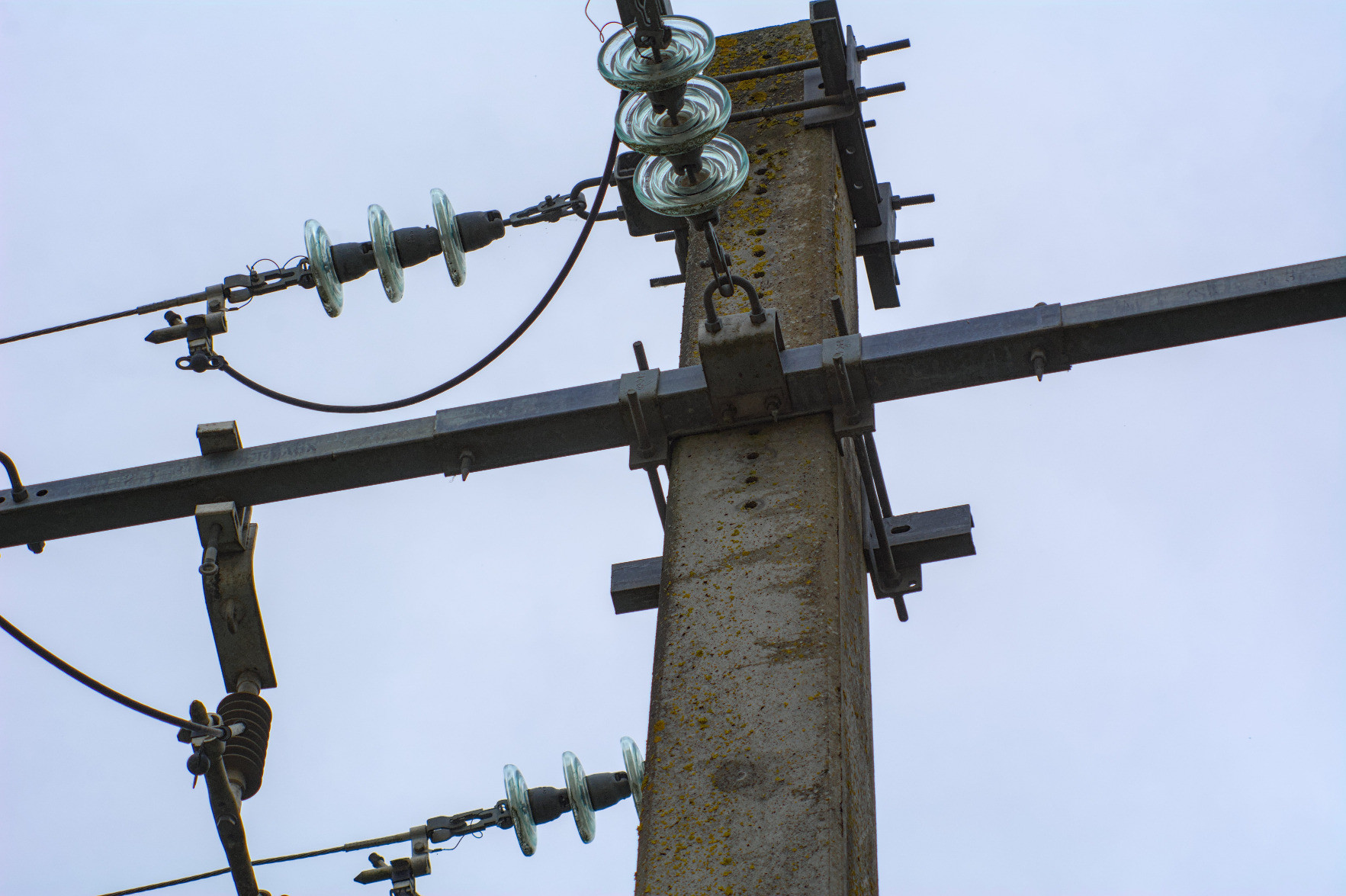 Slanted bottom-up shot of the top part of a power pole, with the round plastic-looking isolators so in focus you can almost see reflections in them. Slanted bottom-up shot of the top part of a power pole, with the round plastic-looking isolators so in focus you can almost see reflections in them.