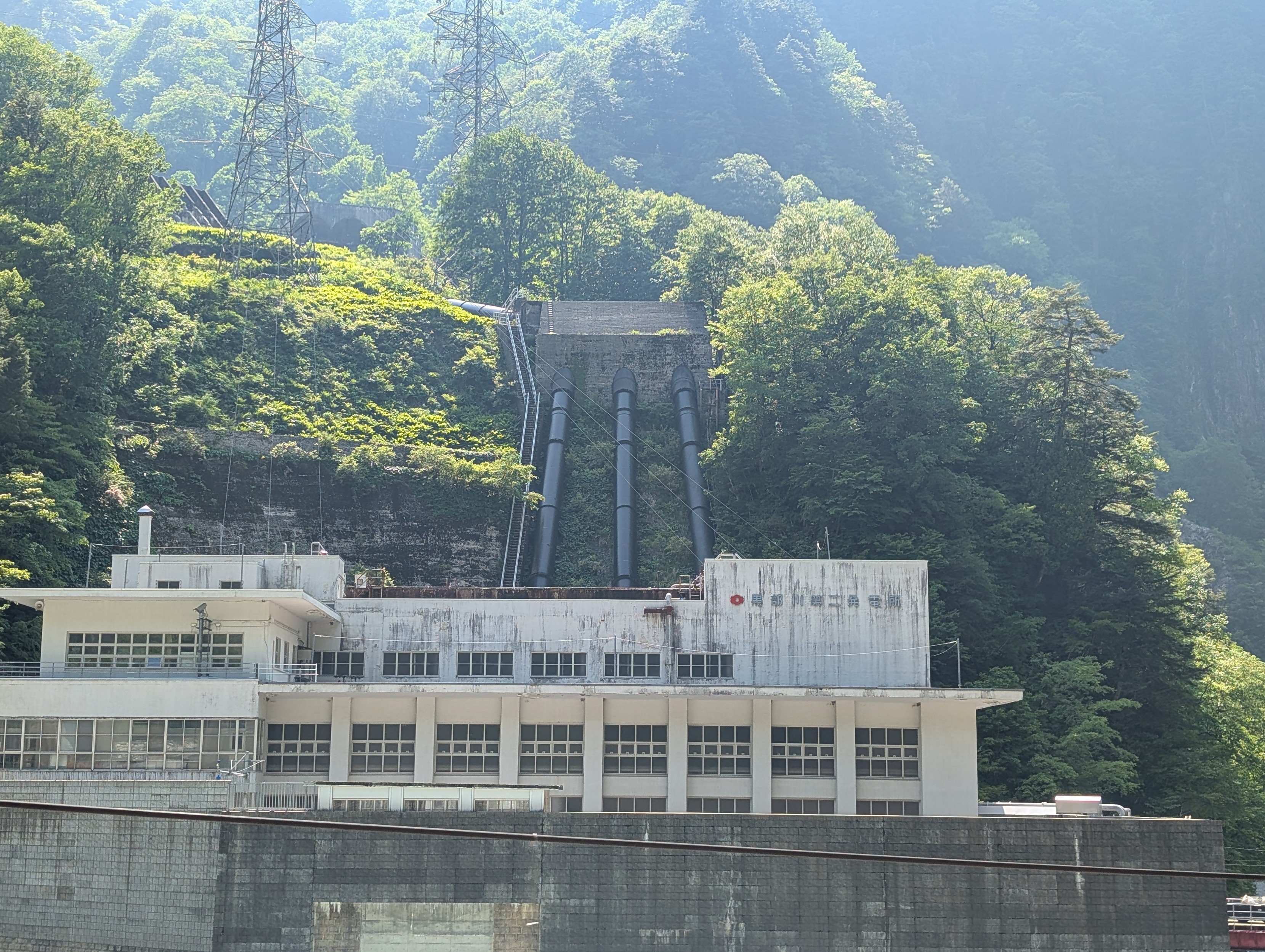 A hydroelectric power plant in a gorge. You can see the water inflow pipes going up the sides, amongst the green tree cover.