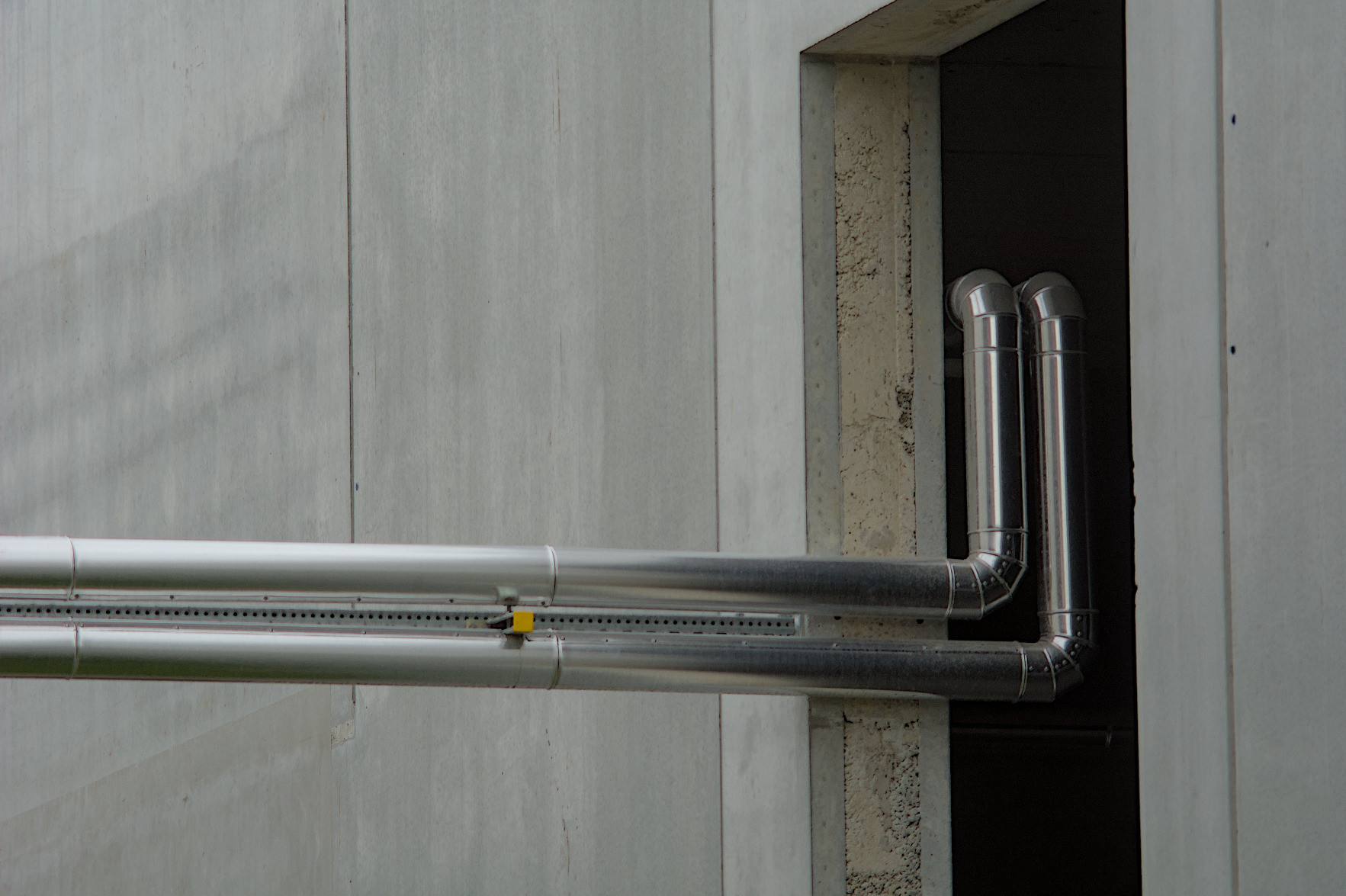 Pipes entering the darkness of a concrete building through a tiny opening. Pipes entering the darkness of a concrete building through a tiny opening.