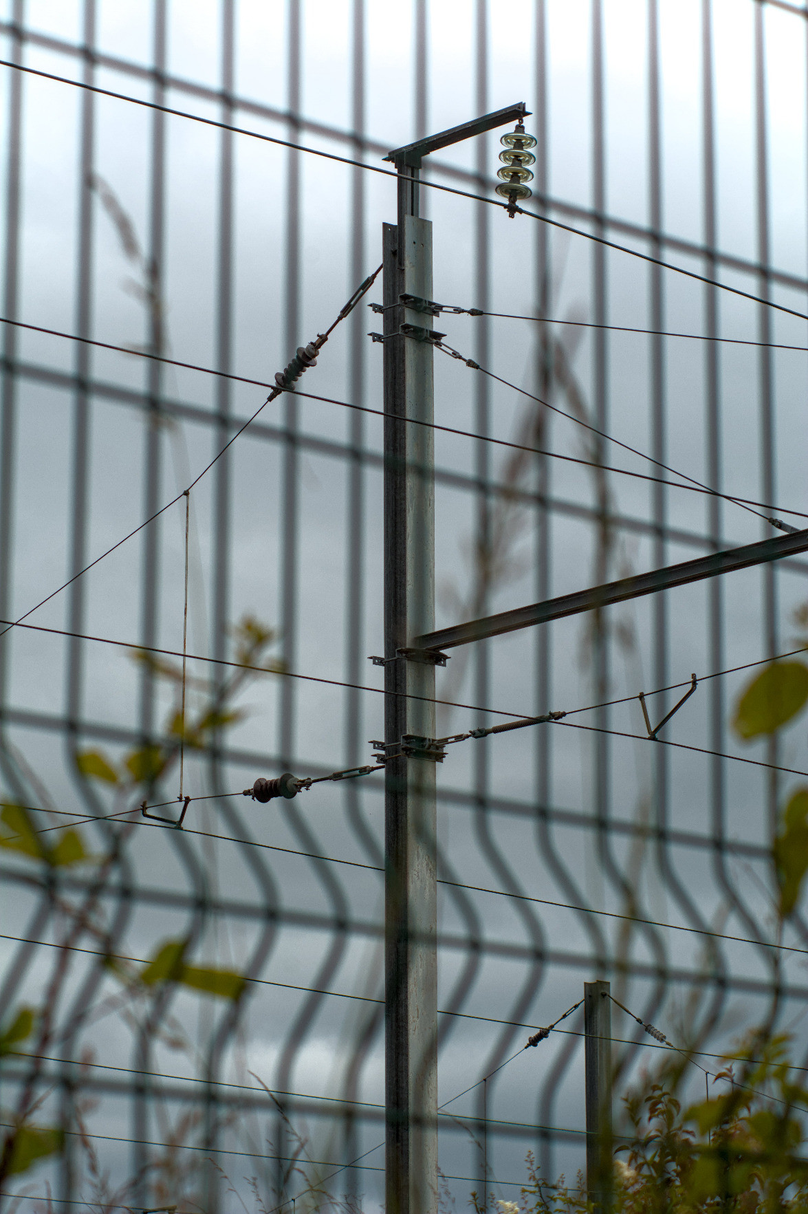 A catenary pole behind a blurry fence, showing rather visible chromatic aberrations. A catenary pole behind a blurry fence, showing rather visible chromatic aberrations.