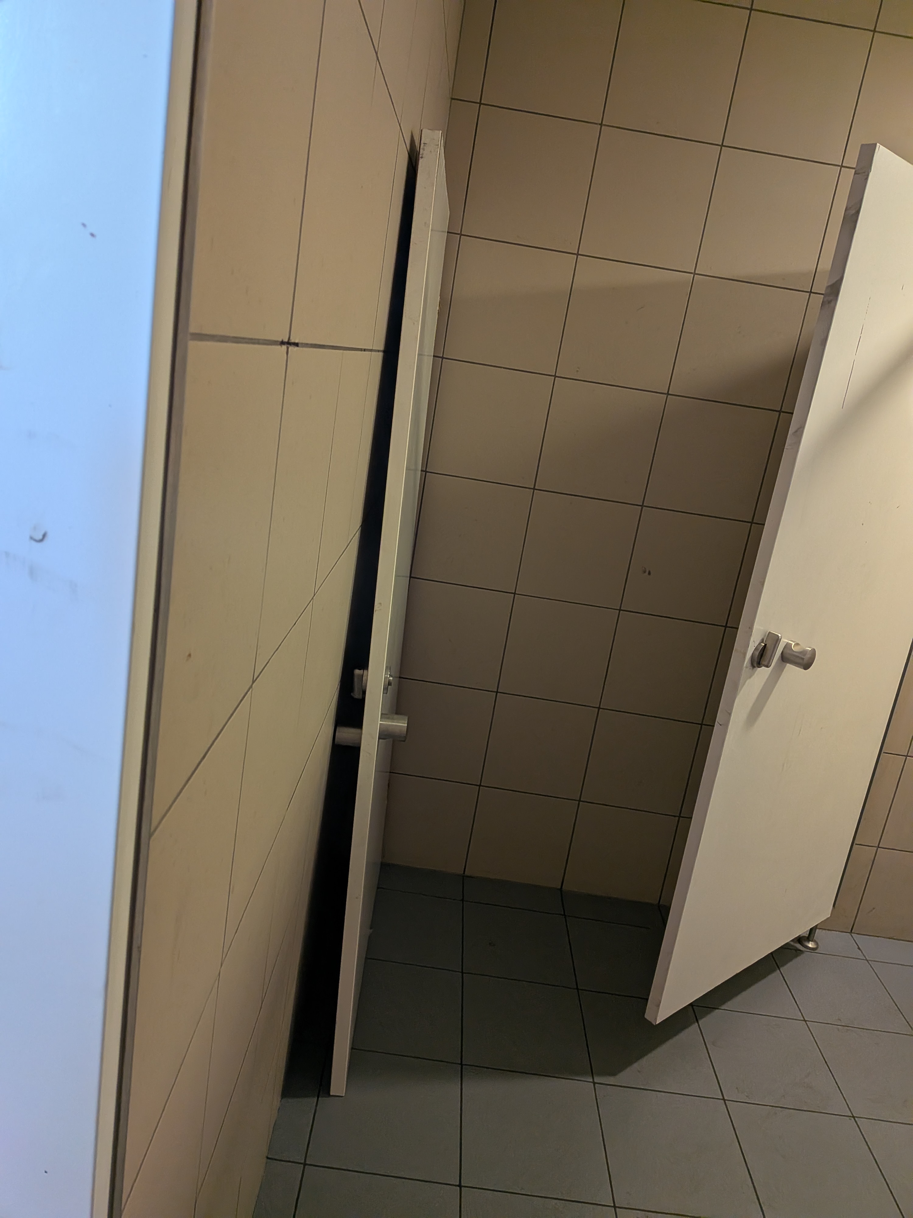 Wnętrze pomieszczenia toalety publicznej z stojącymi opartymi o ścianę drzwiami