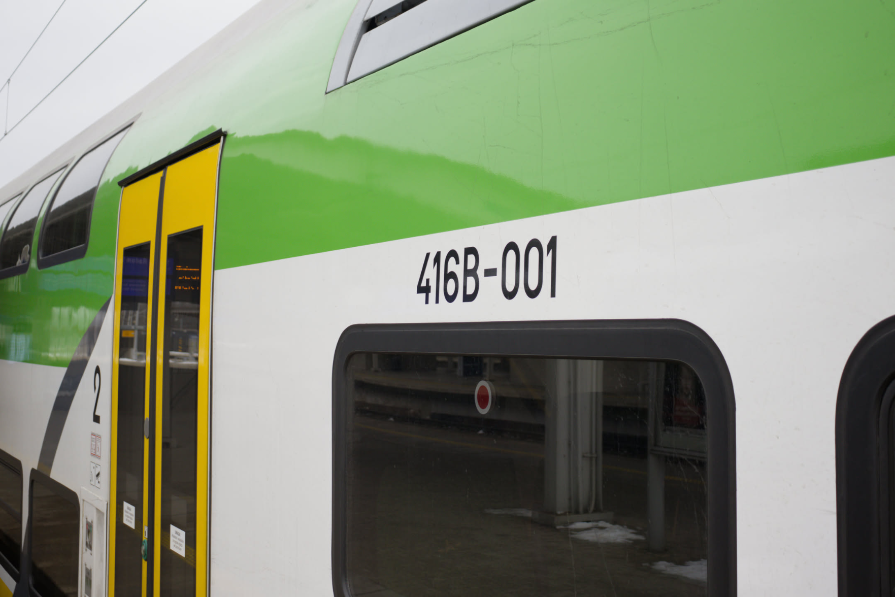 a close-up on the side of a green and white train (with yellow doors), showcasing the marking "416B-001" a close-up on the side of a green and white train (with yellow doors), showcasing the marking "416B-001"