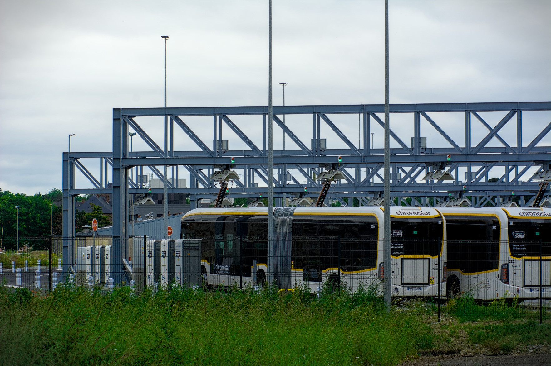 Chronostar buses at a recharge station, they’re all parked under gigantic beams holding jaws that contact on their pantograph to charge them. Chronostar buses at a recharge station, they’re all parked under gigantic beams holding jaws that contact on their pantograph to charge them.