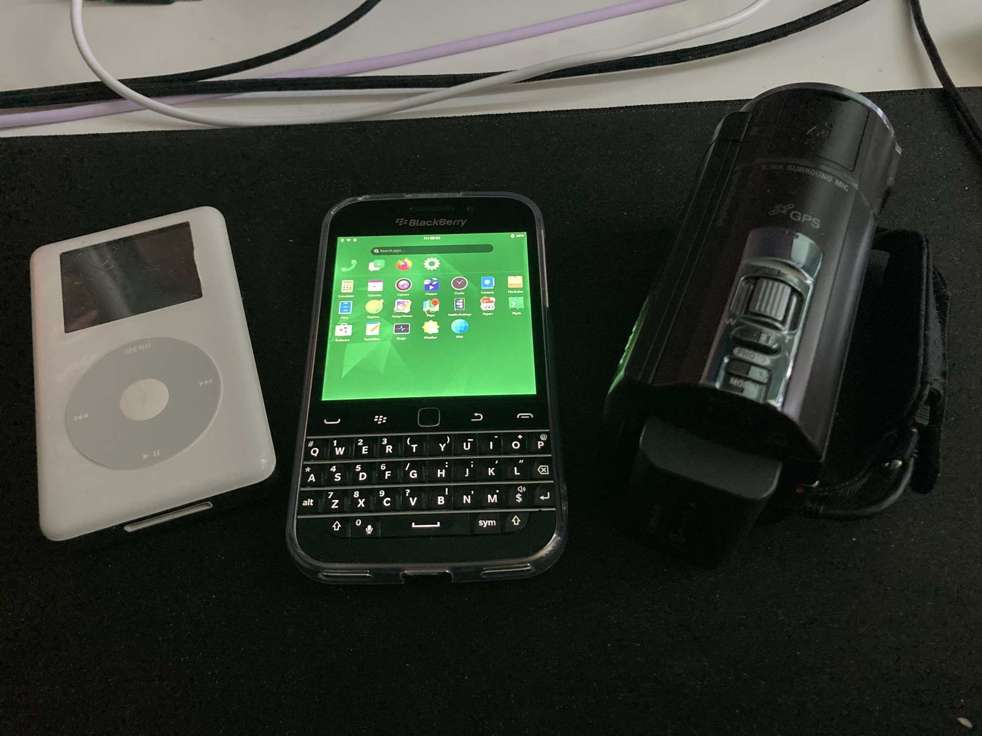 Picture of a 4th Gen iPod, Zinwa Q25 (BlackBerry Classic restomod running Droidian) and Sony CX-590V camcorder on my desk