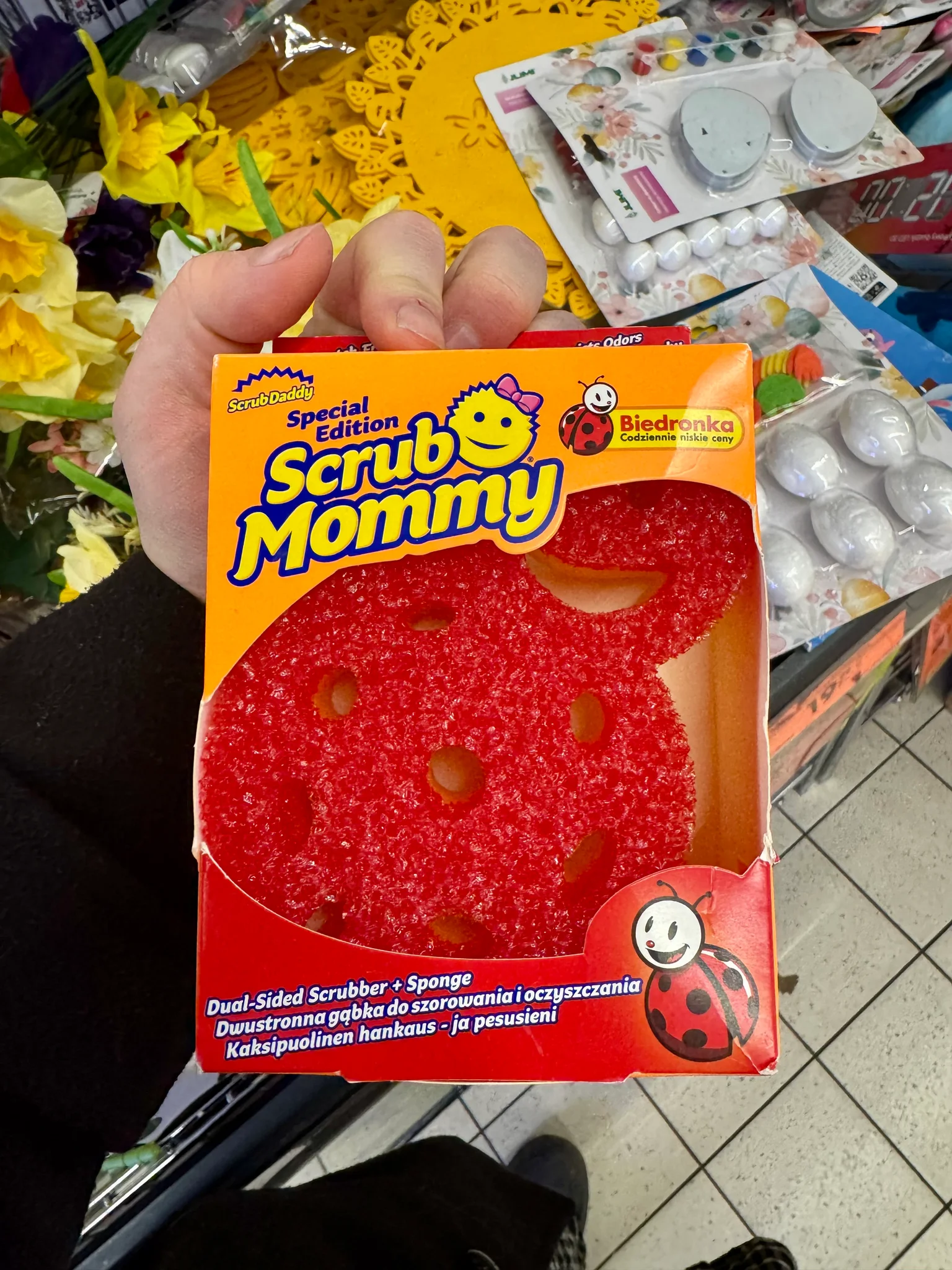 A Scrub Mommy brand sponge in a ladybug shape with Biedronka branding on the packaging.