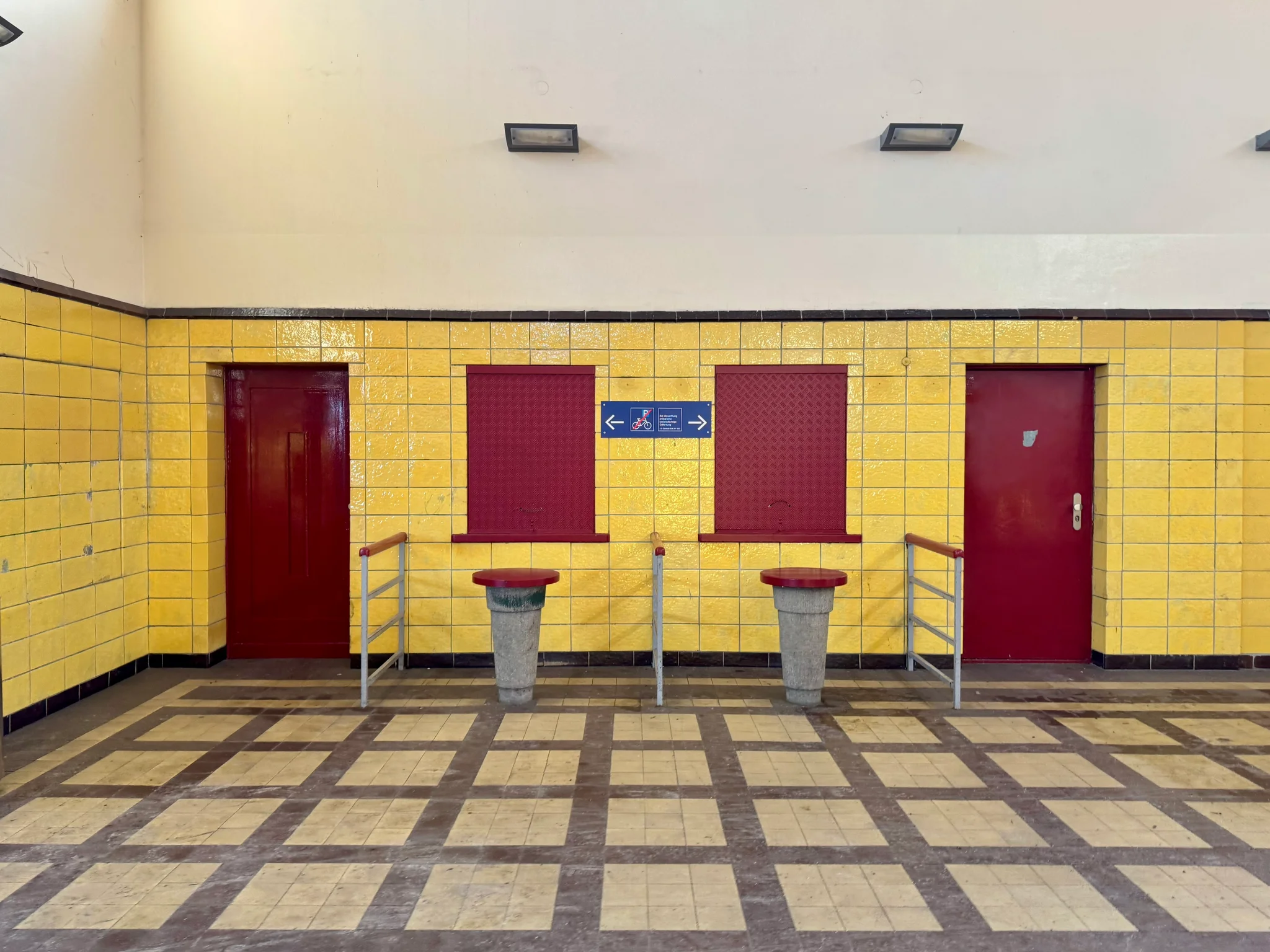 Former ticketing facilities, nor boarded up with red surfaces, surrounded by two red doors, contrasting with the yellow tiles surrounding it. There is a nice symmetry in the image, just wish I had set up the shot a bit nicer. Station Messe-Süd